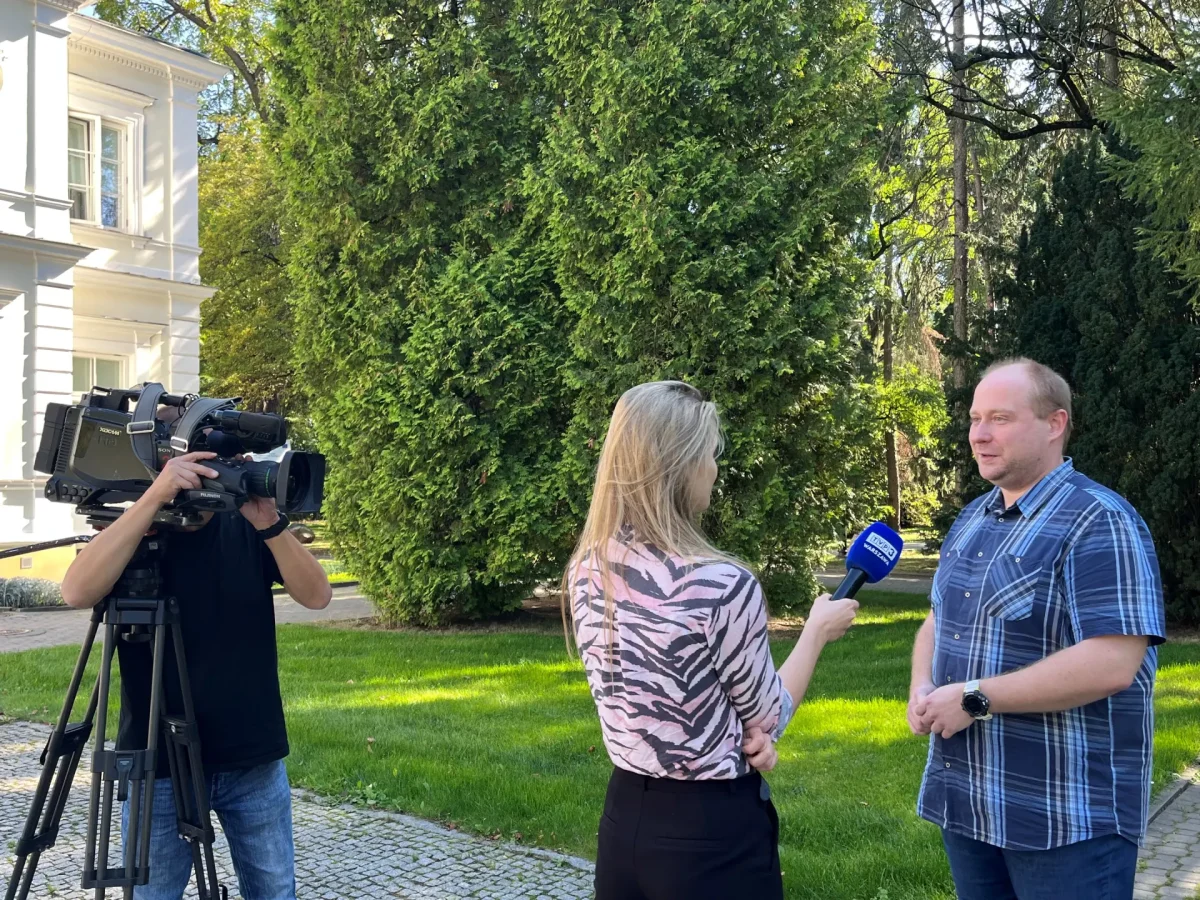 trzy osoby przed rektoratem nagrywająca reportaż